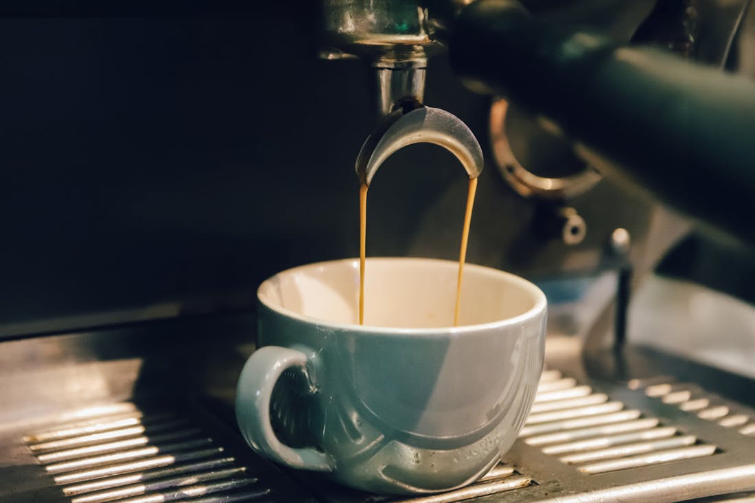 Свежий эспрессо стекает в белую чашку